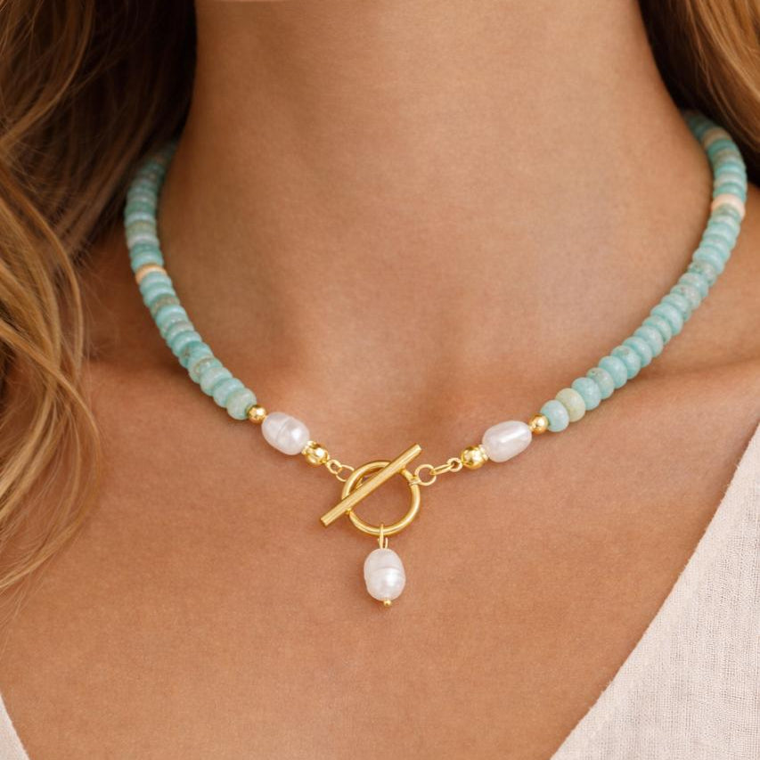 Necklace with turquoise beads and a gold clasp and faux pearl pendant